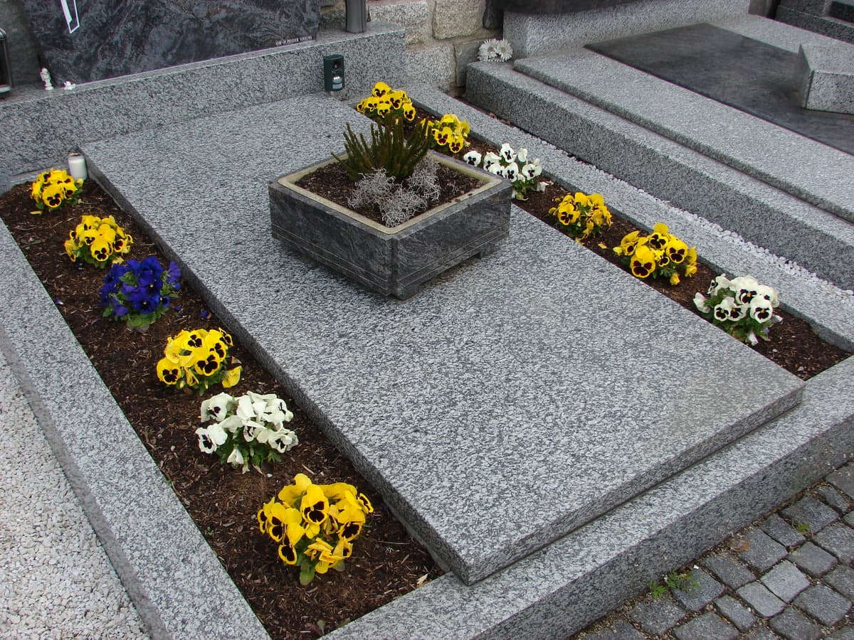 Schlichte Grabanlage aus Hellgranit mit Blumenschmuck